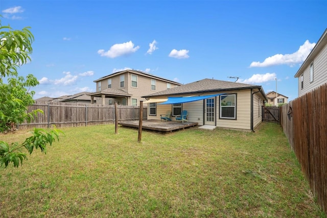 rear view of house featuring a lawn, a wooden deck, and a fenced backyard