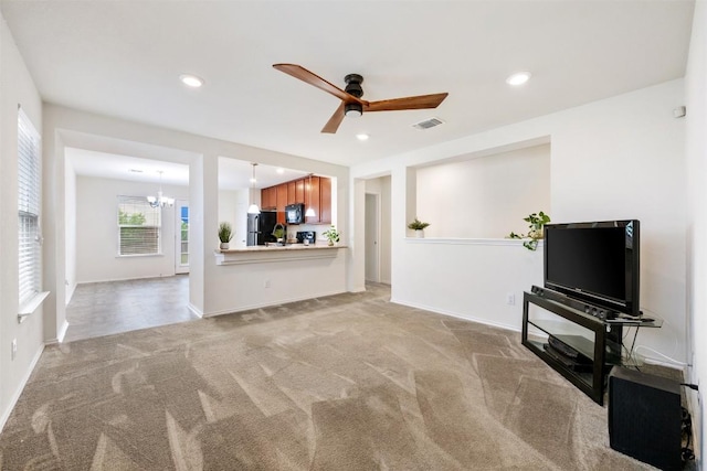 unfurnished living room featuring recessed lighting, ceiling fan with notable chandelier, baseboards, and light carpet