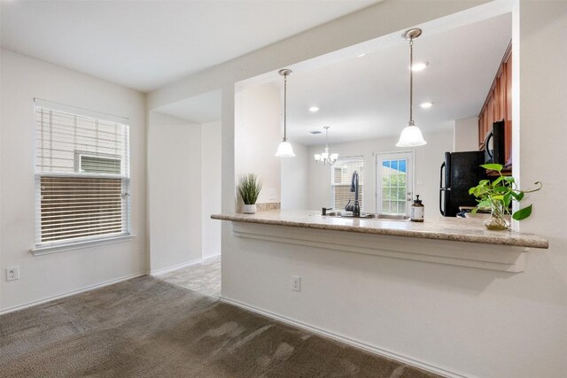 kitchen with hanging light fixtures, carpet, black appliances, a sink, and a peninsula