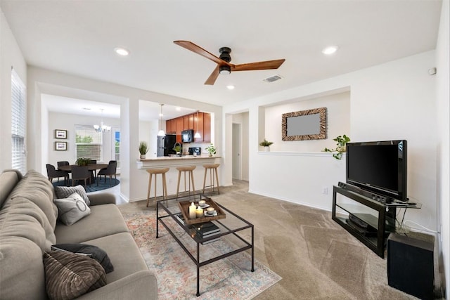 living room with recessed lighting, ceiling fan with notable chandelier, and light colored carpet