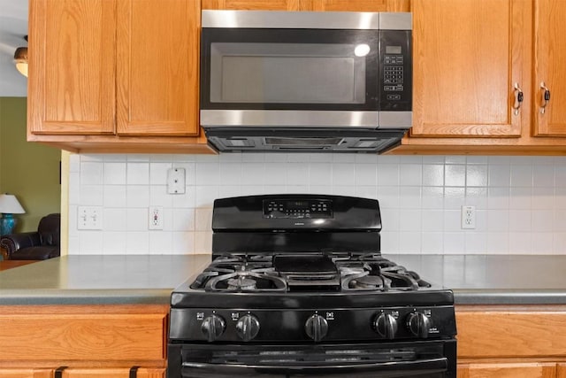 kitchen with black range with gas stovetop, stainless steel microwave, and backsplash