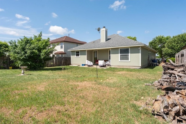 back of house featuring fence, a chimney, a lawn, and a shingled roof