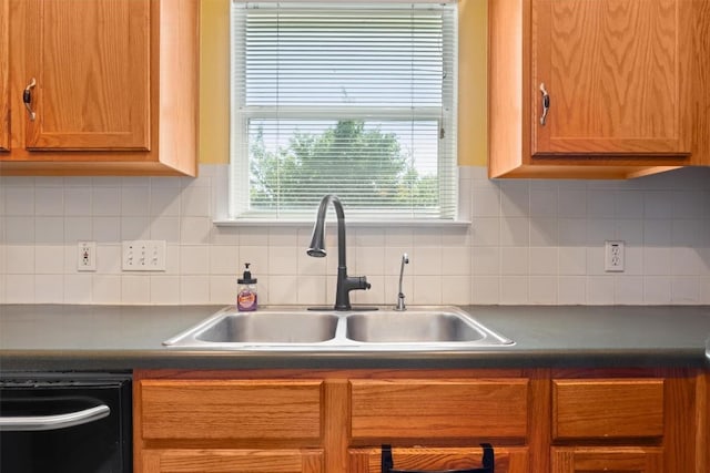 kitchen with decorative backsplash, dark countertops, dishwasher, and a sink
