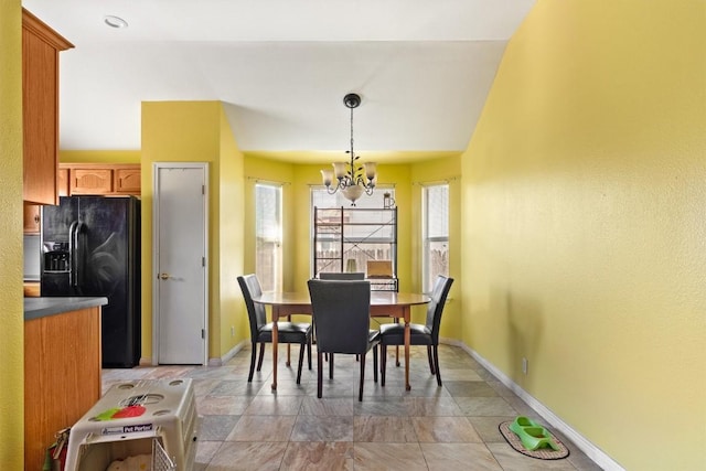 dining area featuring a chandelier, baseboards, and stone finish floor