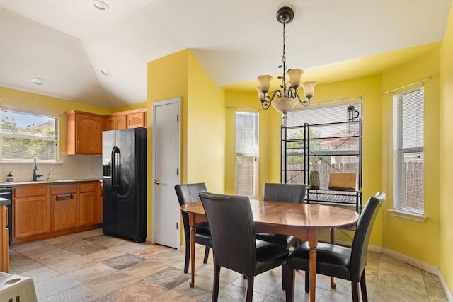 dining area featuring an inviting chandelier, a healthy amount of sunlight, lofted ceiling, and baseboards