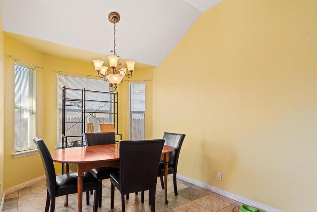 dining area with baseboards, an inviting chandelier, light tile patterned flooring, and vaulted ceiling