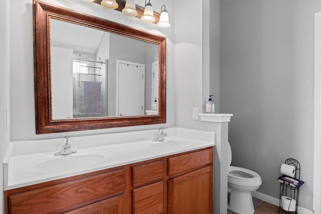 bathroom with baseboards, toilet, double vanity, and a sink