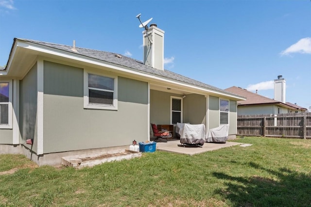 back of property with a patio, a lawn, a chimney, and fence