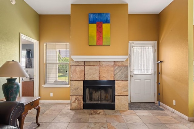 living area featuring a tiled fireplace and baseboards