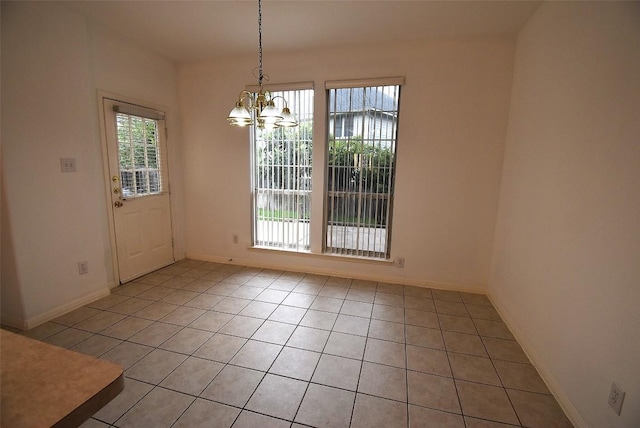 unfurnished dining area featuring light tile patterned floors, a notable chandelier, and baseboards