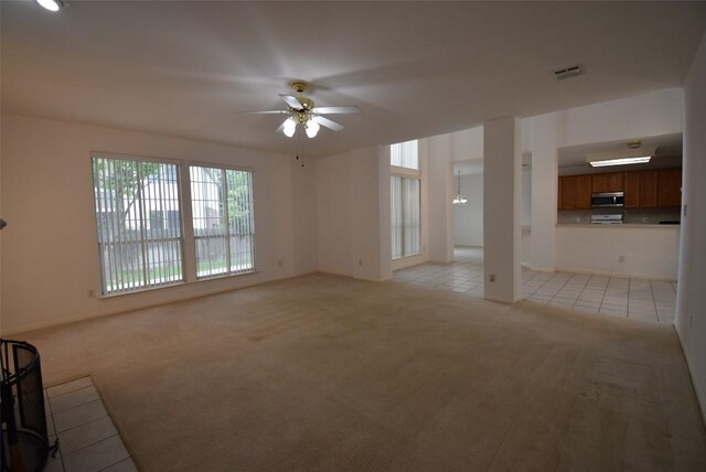 unfurnished living room with visible vents, ceiling fan, light tile patterned flooring, and light colored carpet