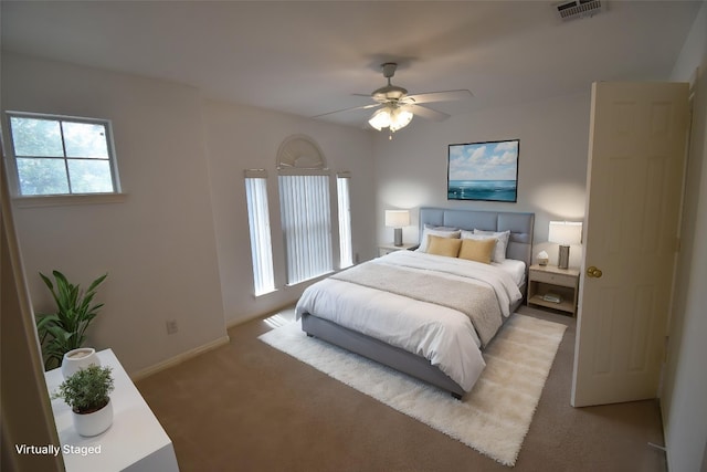bedroom featuring a ceiling fan, visible vents, light carpet, and baseboards