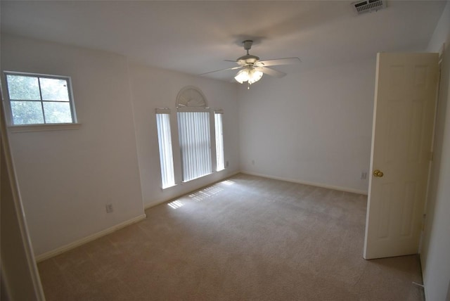 spare room with visible vents, a ceiling fan, baseboards, and light carpet