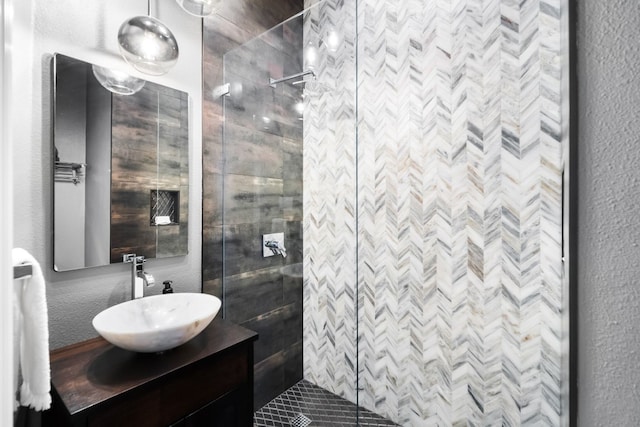 bathroom featuring a stall shower, a textured wall, and vanity