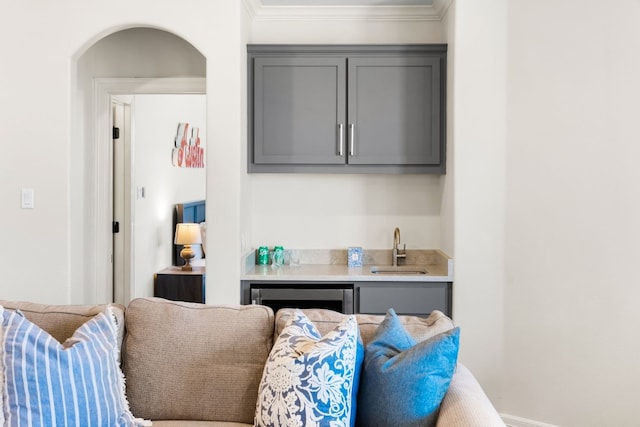 interior space featuring arched walkways, crown molding, indoor wet bar, and a sink