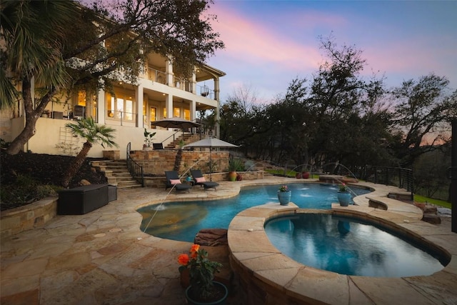 view of swimming pool featuring a pool with connected hot tub, stairs, fence, and a patio area