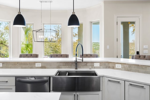 kitchen with a sink, light countertops, an inviting chandelier, dishwasher, and ornamental molding