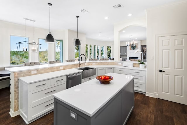 kitchen with a sink, a notable chandelier, a spacious island, light countertops, and stainless steel dishwasher