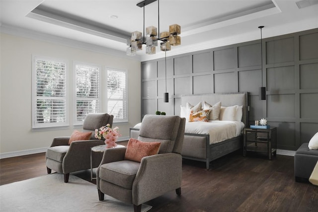 bedroom featuring dark wood-type flooring, an inviting chandelier, a decorative wall, and a tray ceiling