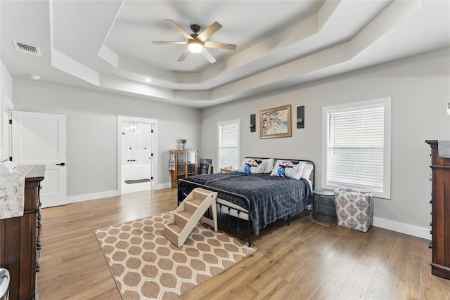 725 Winding Vw, New Braunfels, TX 78132 - bedroom with a raised ceiling, baseboards, visible vents, and light wood-style floors