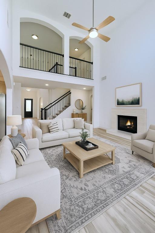 313 El Socorro Ln, Austin, TX 78732 - living area featuring a high ceiling, ceiling fan, wood finished floors, a lit fireplace, and arched walkways