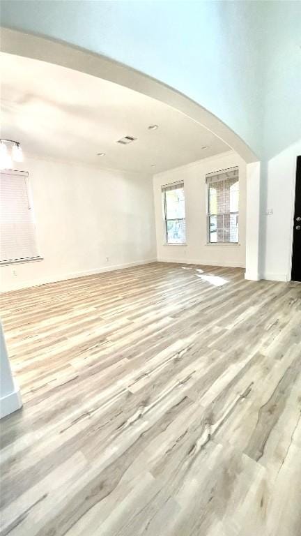 313 El Socorro Ln, Austin, TX 78732 - unfurnished living room featuring light wood-type flooring, arched walkways, and baseboards