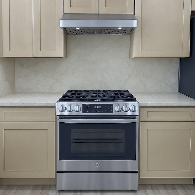 313 El Socorro Ln, Austin, TX 78732 - kitchen with stainless steel gas range, backsplash, exhaust hood, and light countertops