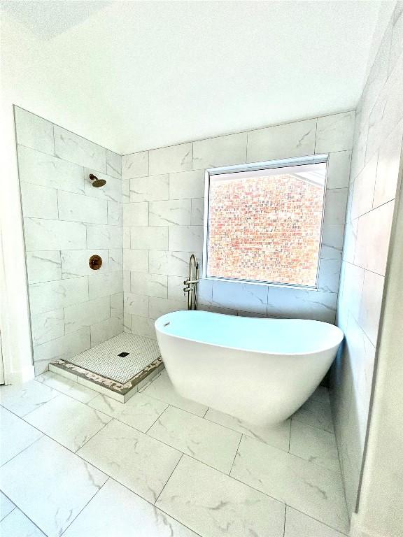 313 El Socorro Ln, Austin, TX 78732 - bathroom with marble finish floors, tiled shower, tile walls, and a soaking tub