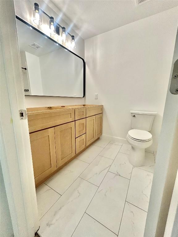 313 El Socorro Ln, Austin, TX 78732 - bathroom featuring vanity, visible vents, toilet, and marble finish floor