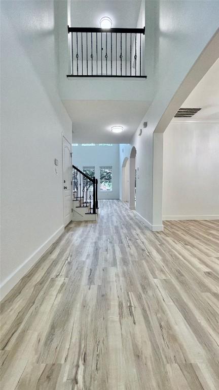 313 El Socorro Ln, Austin, TX 78732 - unfurnished living room with a high ceiling, arched walkways, stairs, baseboards, and wood finished floors