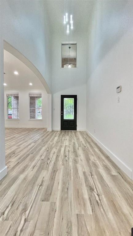 313 El Socorro Ln, Austin, TX 78732 - foyer entrance with baseboards, arched walkways, light wood-style flooring, and plenty of natural light