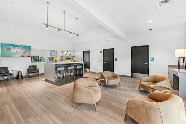 living room with light wood-style floors, visible vents, baseboards, beam ceiling, and high vaulted ceiling