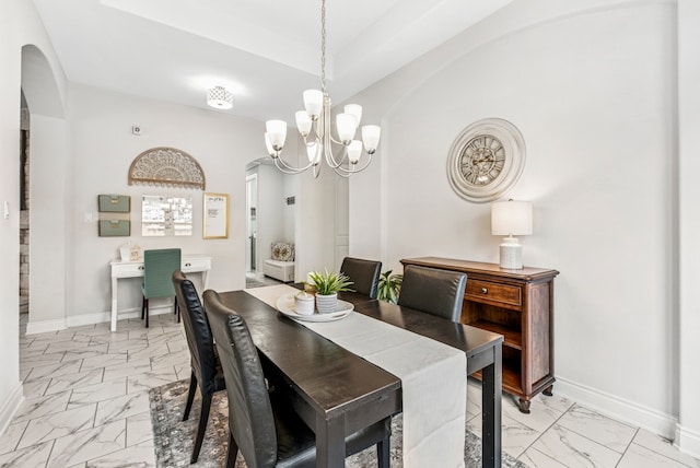 dining space featuring baseboards, a notable chandelier, marble finish floor, and arched walkways