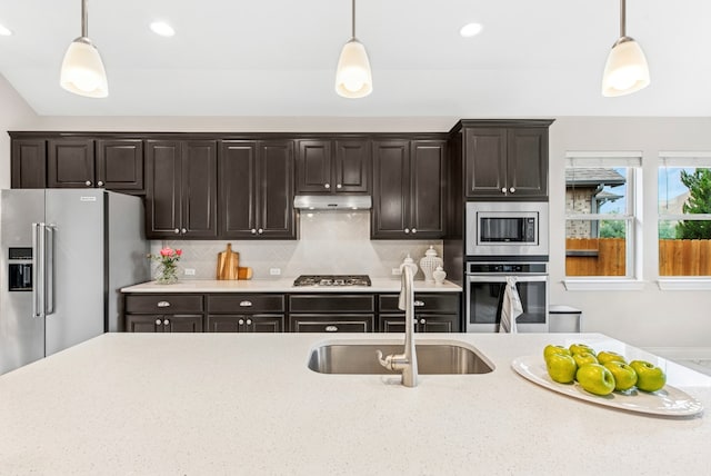kitchen with pendant lighting, stainless steel appliances, a sink, and under cabinet range hood