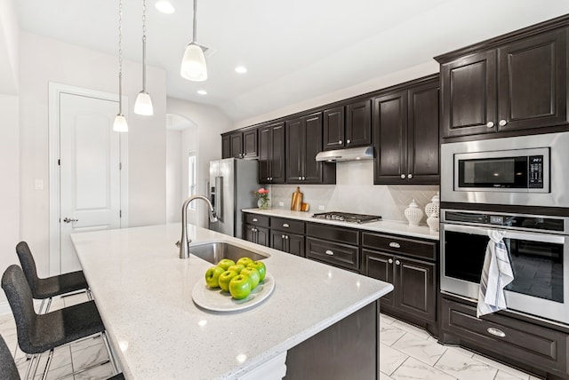 kitchen featuring a sink, stainless steel appliances, a breakfast bar, marble finish floor, and arched walkways