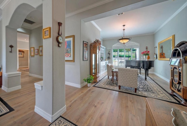 foyer with crown molding, visible vents, baseboards, and light wood-style floors