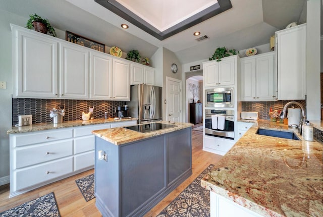 kitchen featuring a sink, stainless steel appliances, a center island, visible vents, and white cabinetry