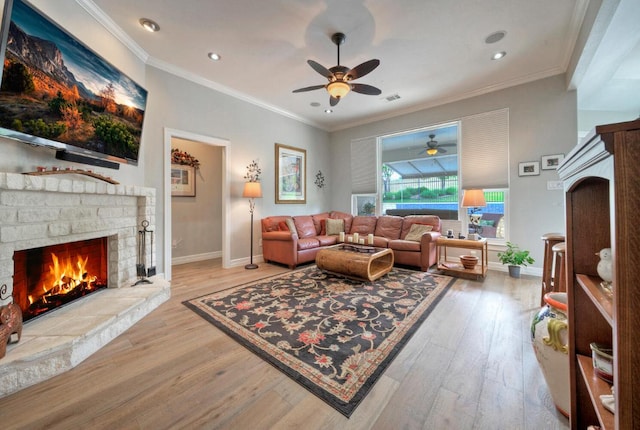 living room with wood finished floors, ceiling fan, a brick fireplace, visible vents, and crown molding