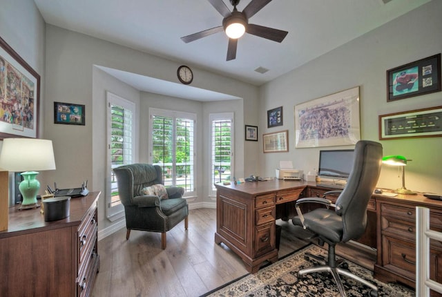 home office featuring baseboards, visible vents, a ceiling fan, and light wood-style flooring