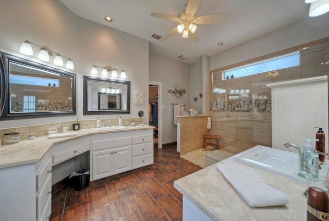 bathroom featuring wood finished floors, walk in shower, ceiling fan, vanity, and visible vents