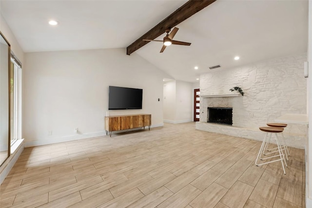 7310 Broken Arrow Ln, Austin, TX 78745 - unfurnished living room featuring light wood finished floors, vaulted ceiling with beams, a ceiling fan, visible vents, and a stone fireplace
