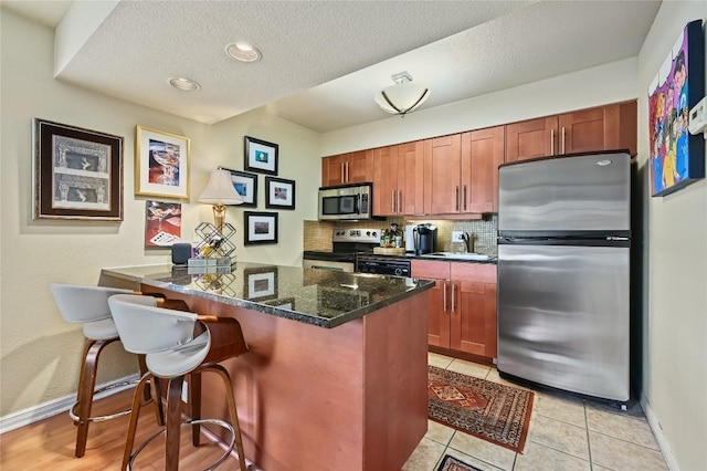 7685 Northcross Dr Unit 304, Austin, TX 78757 - kitchen featuring stainless steel appliances, a breakfast bar, backsplash, a peninsula, and a textured ceiling