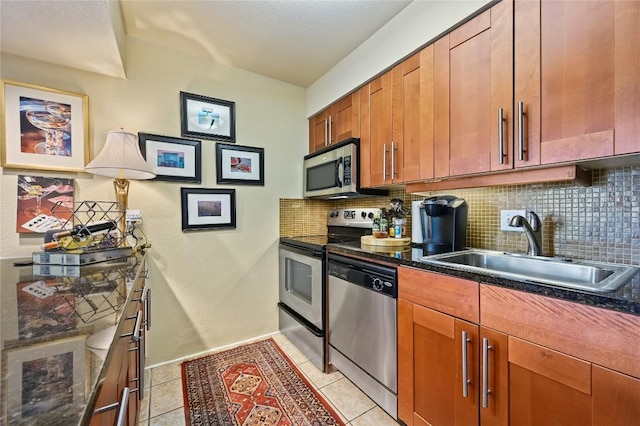7685 Northcross Dr Unit 304, Austin, TX 78757 - kitchen with appliances with stainless steel finishes, decorative backsplash, light tile patterned floors, brown cabinetry, and dark stone countertops