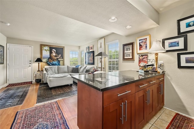 7685 Northcross Dr Unit 304, Austin, TX 78757 - kitchen featuring a textured ceiling, dark stone countertops, a peninsula, and open floor plan