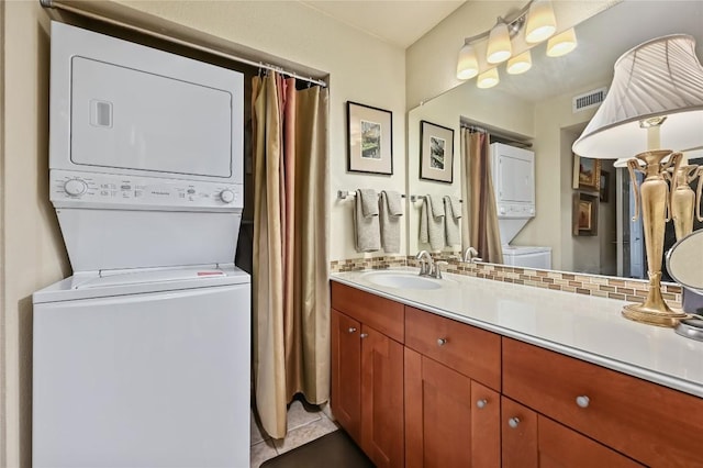 7685 Northcross Dr Unit 304, Austin, TX 78757 - bathroom featuring stacked washer / dryer, vanity, tile patterned flooring, and backsplash