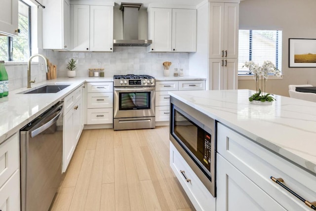 7901 Keswick Dr, Austin, TX 78745 - kitchen with appliances with stainless steel finishes, wall chimney exhaust hood, tasteful backsplash, and white cabinetry