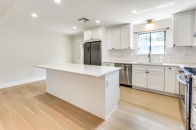 7901 Keswick Dr, Austin, TX 78745 - kitchen with a sink, stainless steel appliances, a center island, tasteful backsplash, and light wood finished floors