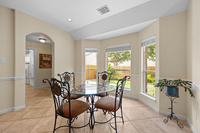 dining area with visible vents, arched walkways, light tile patterned flooring, and plenty of natural light