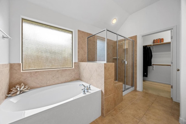 full bathroom featuring a stall shower, a bath, vaulted ceiling, tile patterned floors, and a spacious closet