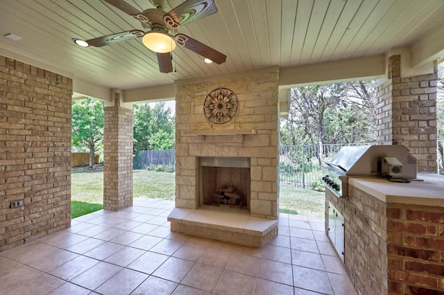 view of patio / terrace with an outdoor stone fireplace, fence, exterior kitchen, and area for grilling